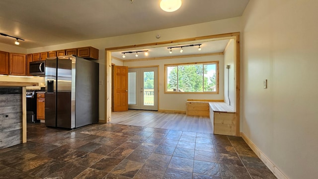 1402 3rd St NE, Staples, MN 56479 - kitchen with appliances with stainless steel finishes, rail lighting, brown cabinetry, and stone tile flooring