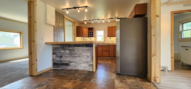 1402 3rd St NE, Staples, MN 56479 - kitchen featuring freestanding refrigerator, brown cabinetry, rail lighting, and light countertops