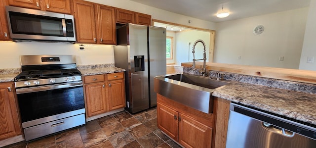 1402 3rd St NE, Staples, MN 56479 - kitchen with appliances with stainless steel finishes, dark stone finish flooring, brown cabinets, and light stone countertops