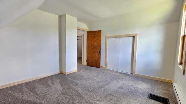 1402 3rd St NE, Staples, MN 56479 - unfurnished bedroom featuring a baseboard heating unit, lofted ceiling, carpet flooring, and a closet