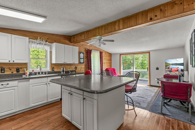 17053 490th St, Shamrock Twp, MN 55760 - kitchen featuring dark countertops, a textured ceiling, wood finished floors, wood walls, and a center island