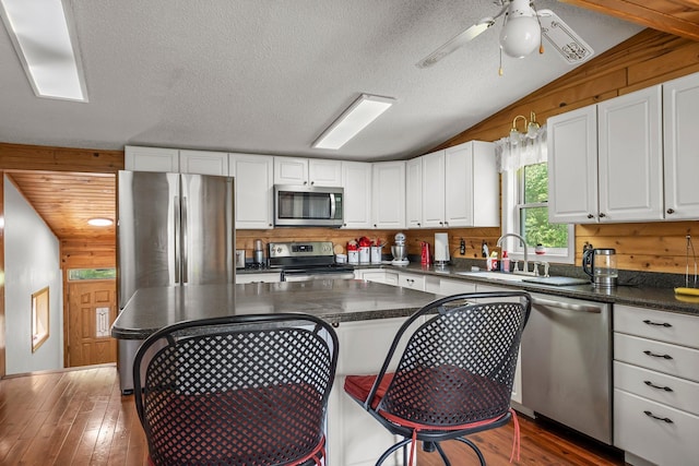 17053 490th St, Shamrock Twp, MN 55760 - kitchen with stainless steel appliances, white cabinetry, dark countertops, vaulted ceiling, and hardwood / wood-style flooring