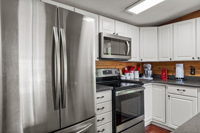17053 490th St, Shamrock Twp, MN 55760 - kitchen with appliances with stainless steel finishes, dark countertops, white cabinetry, a textured ceiling, and dark wood finished floors