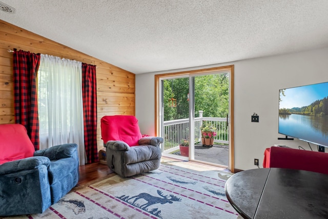 17053 490th St, Shamrock Twp, MN 55760 - living area featuring a textured ceiling, wooden walls, vaulted ceiling, and wood finished floors