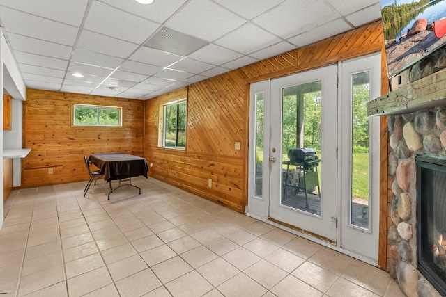 17053 490th St, Shamrock Twp, MN 55760 - doorway to outside with a stone fireplace, wooden walls, light tile patterned floors, and a drop ceiling