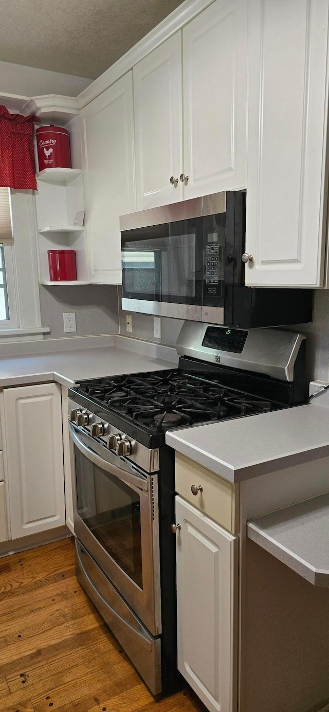 309 5th St SW, Austin, MN 55912 - kitchen with stainless steel appliances, white cabinets, wood finished floors, open shelves, and light countertops