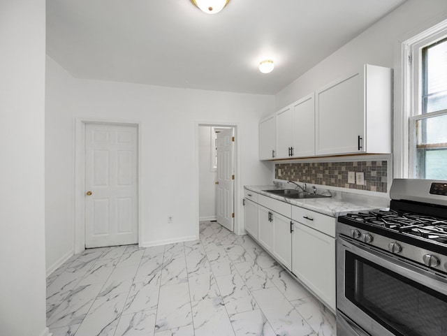 587 Elfelt St, Saint Paul, MN 55103 - kitchen featuring stainless steel range with gas stovetop, decorative backsplash, white cabinets, and light marble finish flooring
