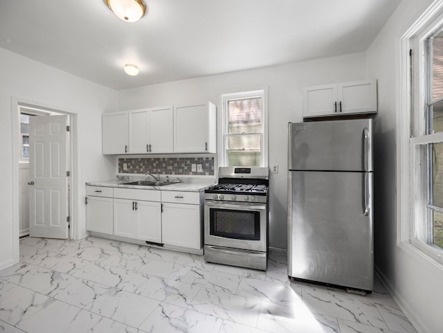 587 Elfelt St, Saint Paul, MN 55103 - kitchen with appliances with stainless steel finishes, light countertops, light marble finish flooring, white cabinetry, and decorative backsplash
