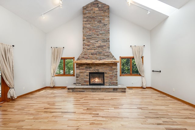 2655 88th Ct W, Northfield, MN 55057 - unfurnished living room with rail lighting, high vaulted ceiling, wood finished floors, and a stone fireplace