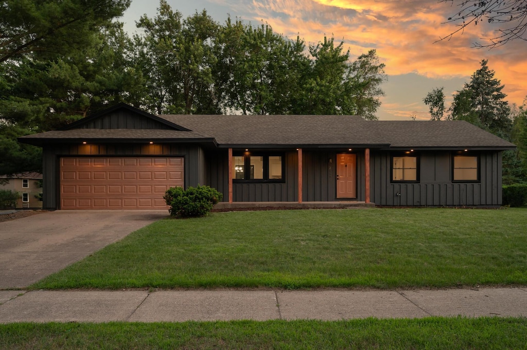 2100 105th Ave NW, Coon Rapids, MN 55433 - view of front facade featuring board and batten siding, a garage, driveway, a porch, and a front lawn