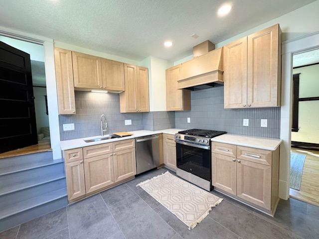 3124 Longfellow Ave, Minneapolis, MN 55407 - kitchen with appliances with stainless steel finishes, premium range hood, light brown cabinetry, backsplash, and light countertops