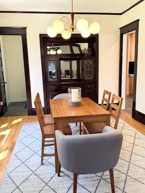3124 Longfellow Ave, Minneapolis, MN 55407 - dining area with light wood-type flooring, a chandelier, and ornamental molding