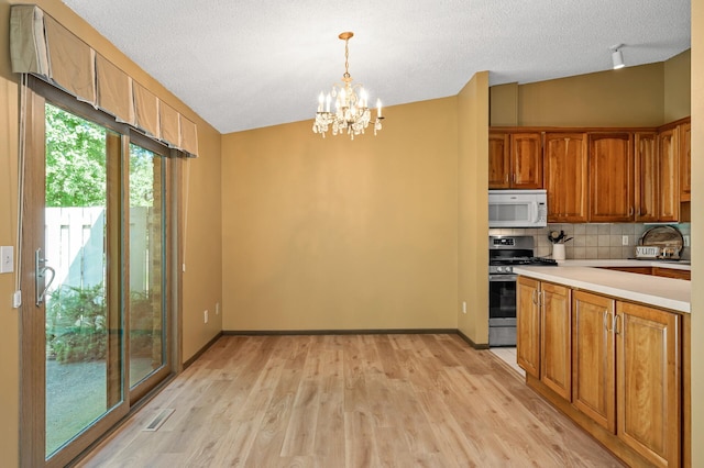 1010 Zanzibar Ln N, Plymouth, MN 55447 - kitchen with stainless steel gas stove, white microwave, a chandelier, light wood-style flooring, and light countertops
