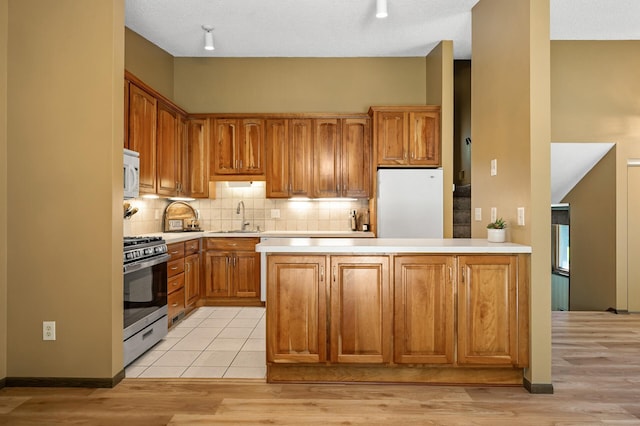 1010 Zanzibar Ln N, Plymouth, MN 55447 - kitchen with white appliances, light countertops, decorative backsplash, light wood-style floors, and a peninsula