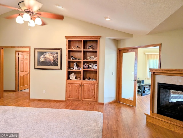506 6th St SE, Little Falls, MN 56345 - unfurnished living room with vaulted ceiling, light wood finished floors, ceiling fan, and a tiled fireplace