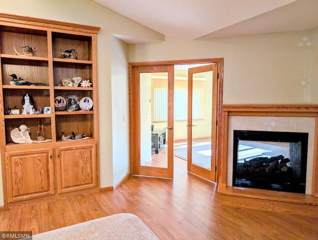 506 6th St SE, Little Falls, MN 56345 - living area with light wood-type flooring, french doors, vaulted ceiling, and a tiled fireplace