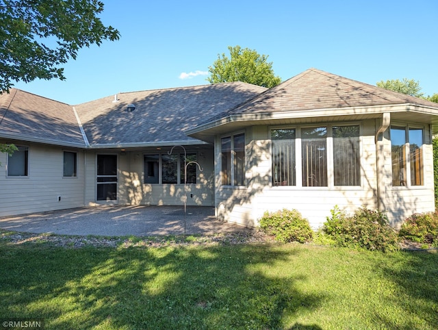 506 6th St SE, Little Falls, MN 56345 - back of property with a lawn, a shingled roof, and a patio area