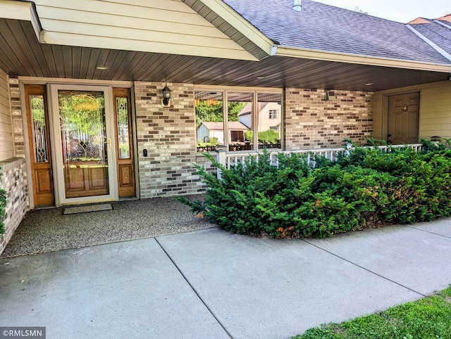 506 6th St SE, Little Falls, MN 56345 - doorway to property with brick siding, a porch, and roof with shingles