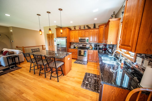 1322 Frontier Rd SE, Salem Twp, MN 55920 - kitchen featuring appliances with stainless steel finishes, brown cabinetry, a breakfast bar area, decorative backsplash, and a center island