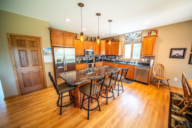 1322 Frontier Rd SE, Salem Twp, MN 55920 - kitchen with stainless steel appliances, light wood finished floors, a kitchen bar, tasteful backsplash, and brown cabinetry
