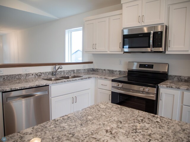 7891 Lost River Rd, Horace, ND 58047 - kitchen with appliances with stainless steel finishes, white cabinetry, light stone countertops, and lofted ceiling