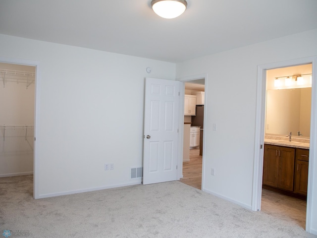 7891 Lost River Rd, Horace, ND 58047 - unfurnished bedroom with a spacious closet, light colored carpet, connected bathroom, and a closet