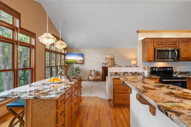 6961 Meadow Ct, Centerville, MN 55038 - kitchen with stainless steel microwave, black electric range, a breakfast bar area, light stone countertops, and brown cabinetry
