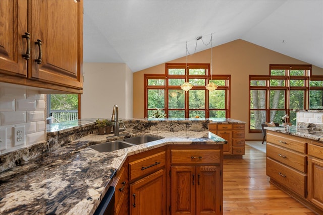 6961 Meadow Ct, Centerville, MN 55038 - kitchen with brown cabinets, light wood finished floors, light stone countertops, lofted ceiling, and a peninsula