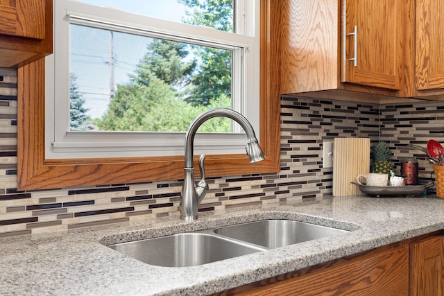 1602 19th Ave SW, Austin, MN 55912 - kitchen featuring backsplash, brown cabinetry, and light stone countertops