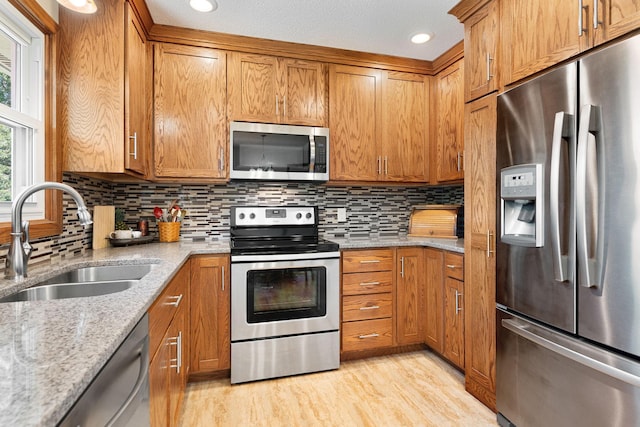 1602 19th Ave SW, Austin, MN 55912 - kitchen with appliances with stainless steel finishes, brown cabinets, light wood finished floors, light stone counters, and recessed lighting