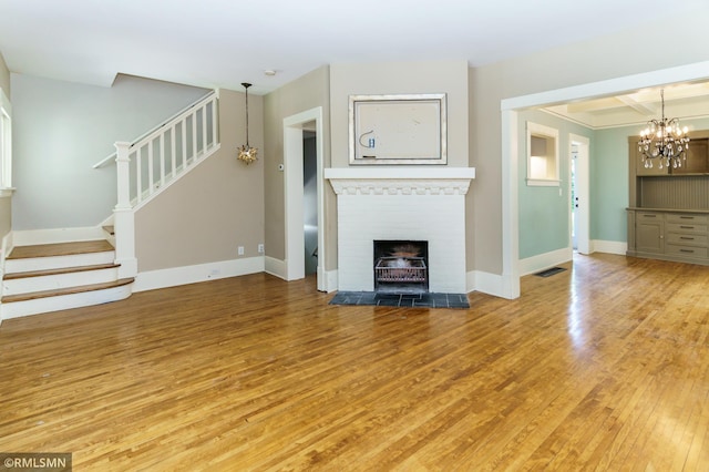 4709 Colfax Ave S, Minneapolis, MN 55419 - unfurnished living room with stairs, light wood-style flooring, a chandelier, and a tile fireplace