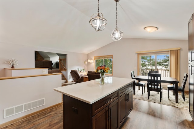 818 Myrtle St, Buffalo, MN 55313 - kitchen with wood finished floors, vaulted ceiling, light countertops, dark brown cabinetry, and pendant lighting