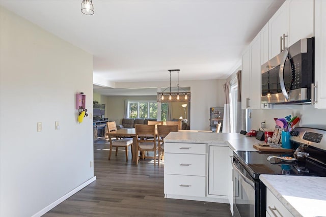 4069 Dublin Rd, Hibbing, MN 55746 - kitchen with appliances with stainless steel finishes, a peninsula, white cabinetry, dark wood-style floors, and light countertops