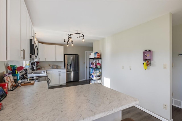4069 Dublin Rd, Hibbing, MN 55746 - kitchen featuring appliances with stainless steel finishes, a peninsula, white cabinetry, dark wood-type flooring, and a chandelier