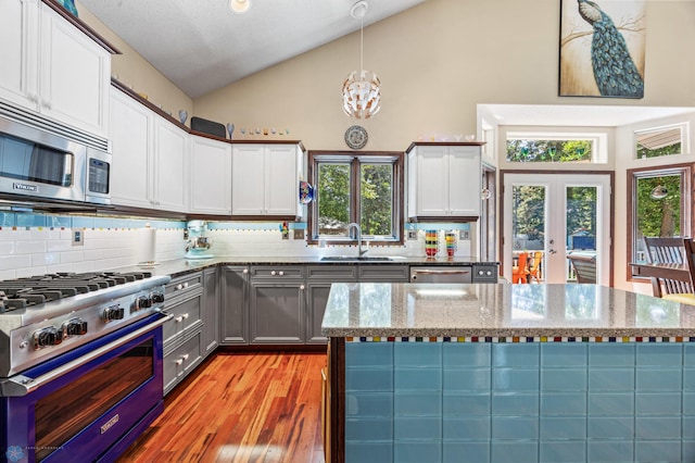 525 20 1/2 Ave E, West Fargo, ND 58078 - kitchen with stainless steel appliances, decorative backsplash, light wood-style flooring, stone countertops, and a chandelier