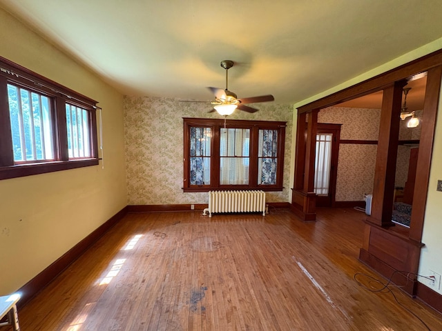 201 3rd St SE, Renville, MN 56284 - unfurnished room featuring radiator heating unit, wallpapered walls, ceiling fan, and wood finished floors