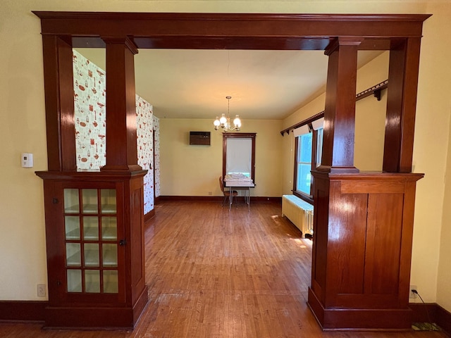 201 3rd St SE, Renville, MN 56284 - hall featuring radiator, wood finished floors, a chandelier, and decorative columns
