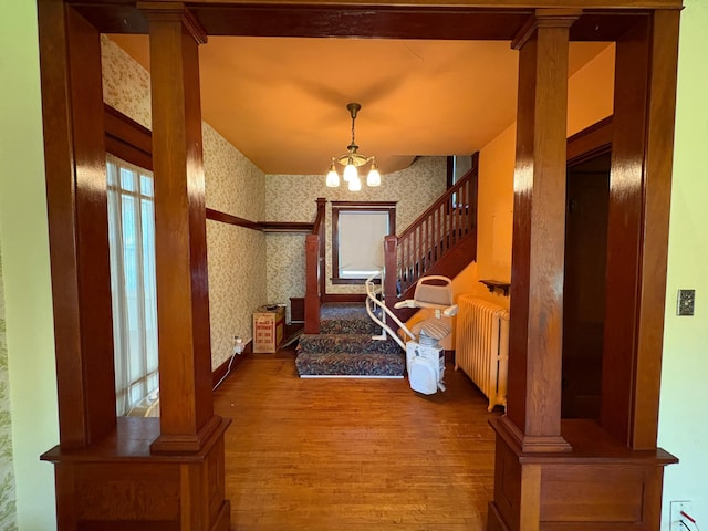 201 3rd St SE, Renville, MN 56284 - entrance foyer with wallpapered walls, wood finished floors, a chandelier, stairs, and radiator heating unit