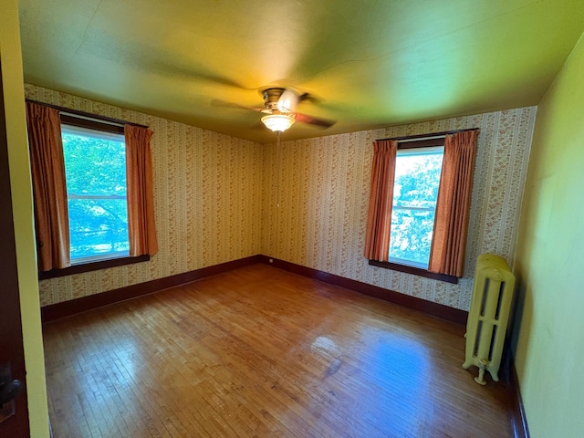 201 3rd St SE, Renville, MN 56284 - unfurnished room featuring radiator, wood finished floors, ceiling fan, and wallpapered walls