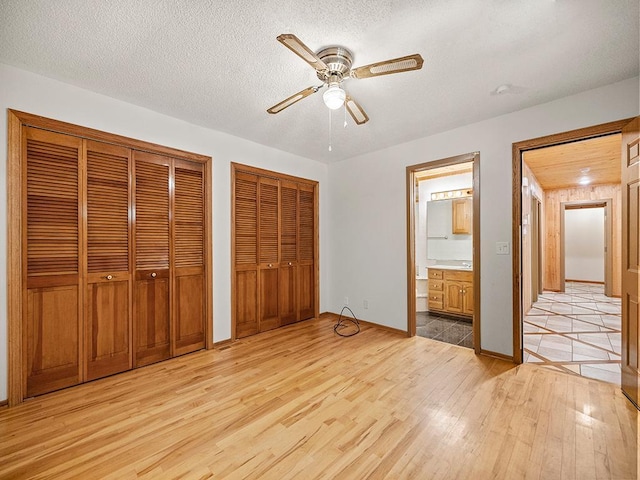 20980 Parkfield Ave, Spring Lake Twp, MN 55352 - unfurnished bedroom featuring light wood-style flooring, multiple closets, connected bathroom, ceiling fan, and a textured ceiling