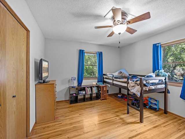 724 2nd Ave S, Buffalo, MN 55313 - bedroom with light wood-style floors, multiple windows, a textured ceiling, and a ceiling fan