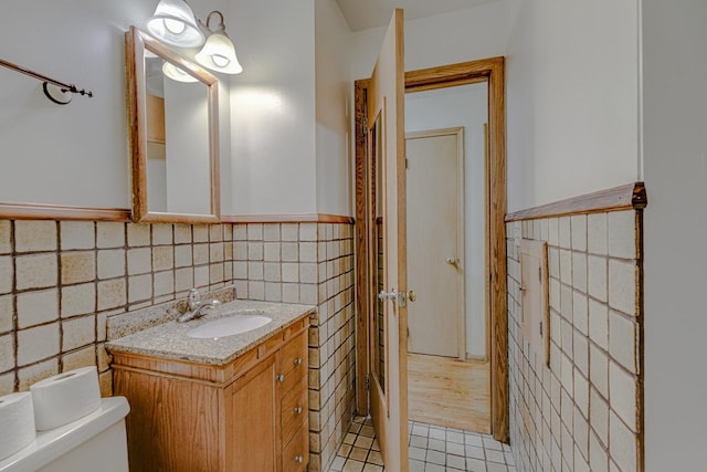1970 Maryknoll Ave, Maplewood, MN 55109 - bathroom featuring tile walls, vanity, tile patterned floors, and a wainscoted wall