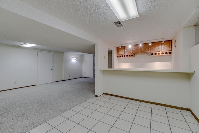 1970 Maryknoll Ave, Maplewood, MN 55109 - kitchen featuring light countertops, a textured ceiling, a peninsula, brown cabinetry, and light carpet