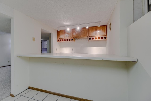 1970 Maryknoll Ave, Maplewood, MN 55109 - kitchen with rail lighting, a textured ceiling, a peninsula, brown cabinets, and light countertops