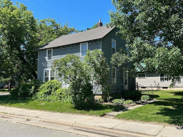 823 5th St, Grand Rapids, MN 55744 - view of home's exterior with a chimney, a yard, and roof with shingles