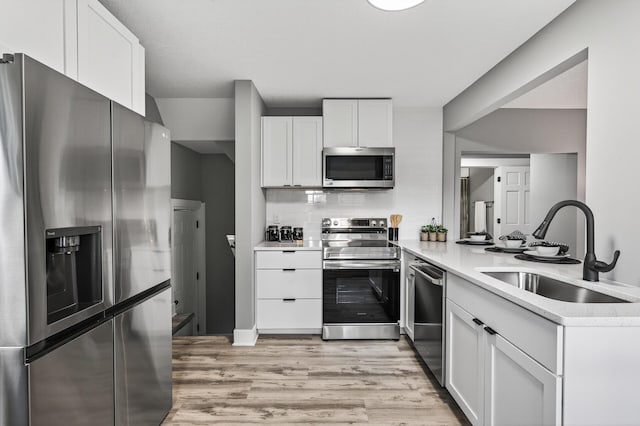 4301 Columbus Ave, Minneapolis, MN 55407 - kitchen with appliances with stainless steel finishes, light countertops, white cabinetry, light wood-type flooring, and a peninsula