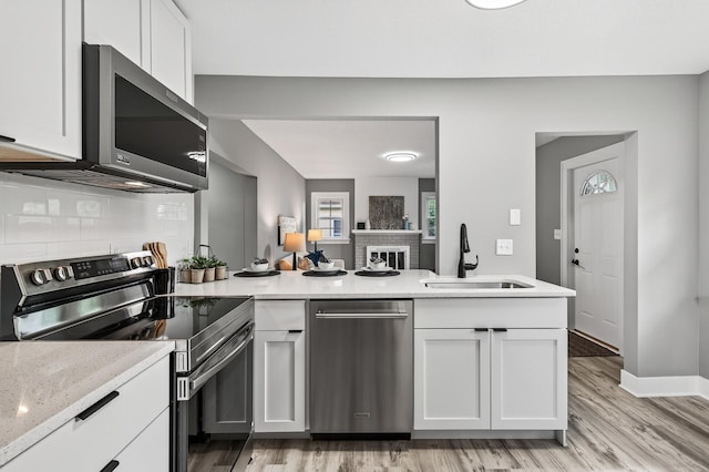 4301 Columbus Ave, Minneapolis, MN 55407 - kitchen with stainless steel appliances, light wood-style floors, backsplash, and white cabinets
