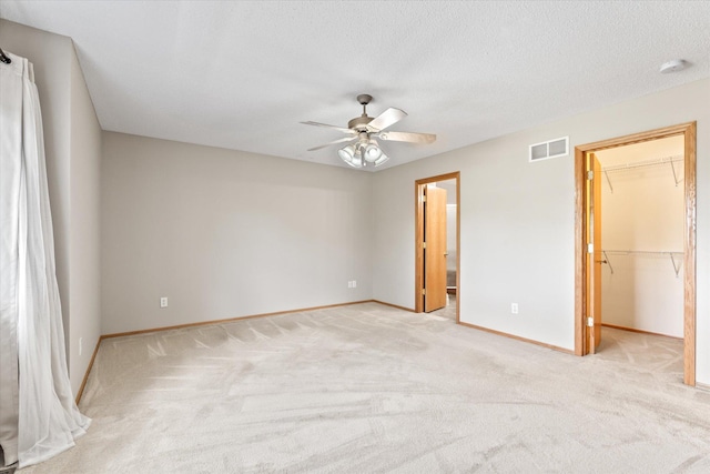 5607 100th Ln N, Brooklyn Park, MN 55443 - unfurnished bedroom with a walk in closet, light carpet, a ceiling fan, and a textured ceiling