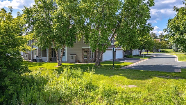 5607 100th Ln N, Brooklyn Park, MN 55443 - view of property hidden behind natural elements featuring an attached garage, a front lawn, and driveway