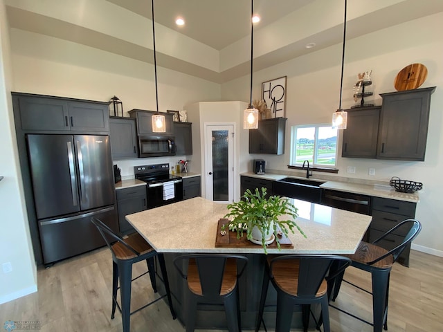 1819 67th Ave S, Fargo, ND 58104 - kitchen with stainless steel appliances, light wood-style flooring, light countertops, a breakfast bar, and hanging light fixtures